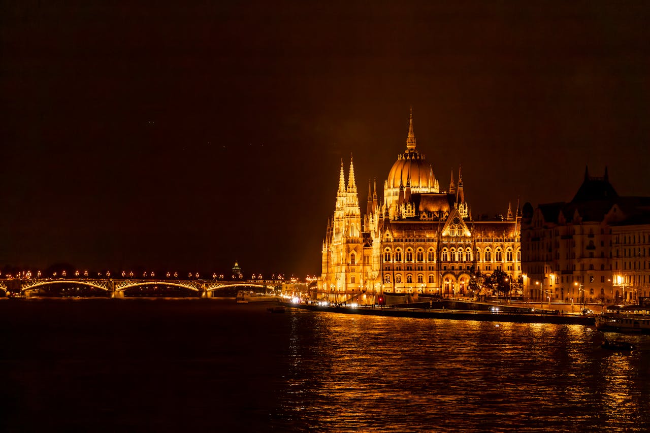 services-01 Stunning view of the illuminated Budapest Parliament and bridge reflecting on the Danube River at night.