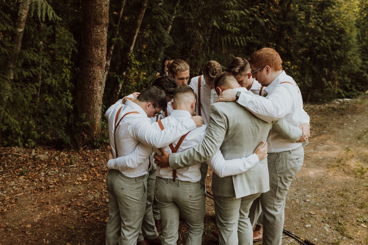 why-choose-us Groomsmen huddle in a supportive circle outdoors, preparing for a wedding ceremony.