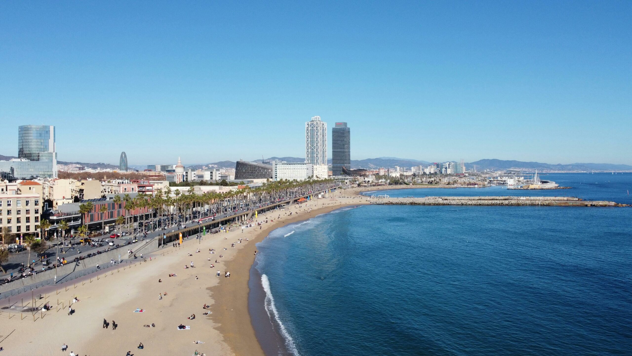 A stunning aerial shot of Barcelona's beach and city skyline on a clear day, capturing the vibrant coast.